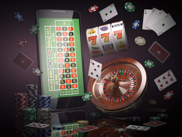 Online casino concept. Mobile phone, roulette with casino chips, slot machine and cards.