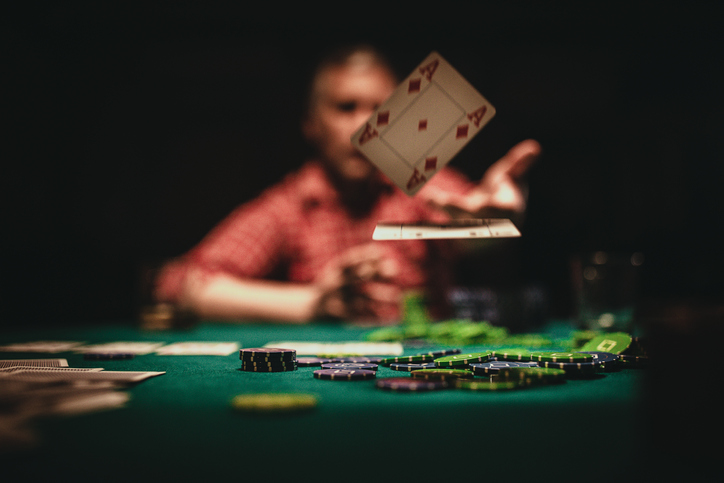 blurred man in background throwing cards on table
