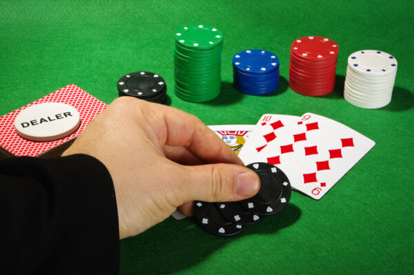 dealer hand on table with cards and poker chips