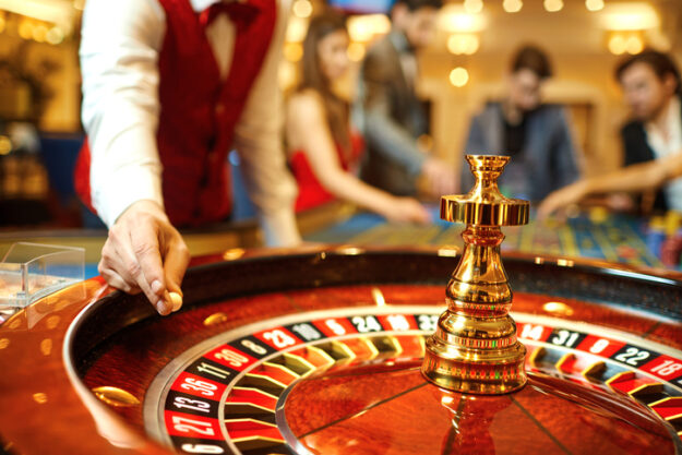Croupier hold a roulette ball over a roulette table