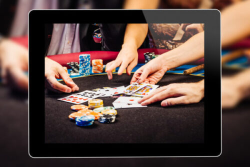 Online Gambling through a tablet with people's hands shown with card and poker chips laying on a table with black felt