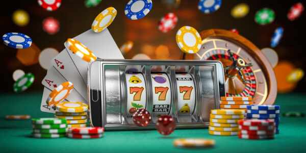 Online casino. Smartphone or mobile phone, slot machine, dice, cards and roulette on a green table in casino.