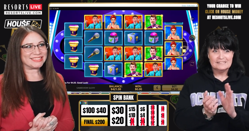 An image of a resort live house money game. There are two women clapping while presenting a slot game. 