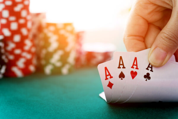 Woman hand revealing four aces with red and green chips stacked on the left side.