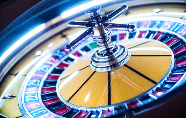 Closeup side view of roulette wheel in casino spinning after bets have been placed. It's lit blue by neon lights. Tilt shot. rtp in roulette calculated.