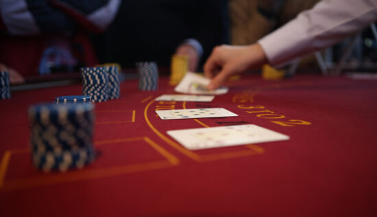 cards being places one after another on a red casino table, people talking about the history of blackjack